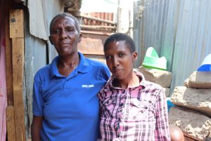 Pauline and her mother standing next to each other holding hands outside their home. 