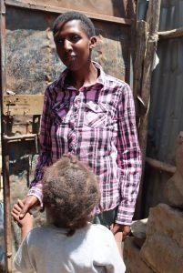 Mary holding her niece's hand outside their home in Mukuru. 